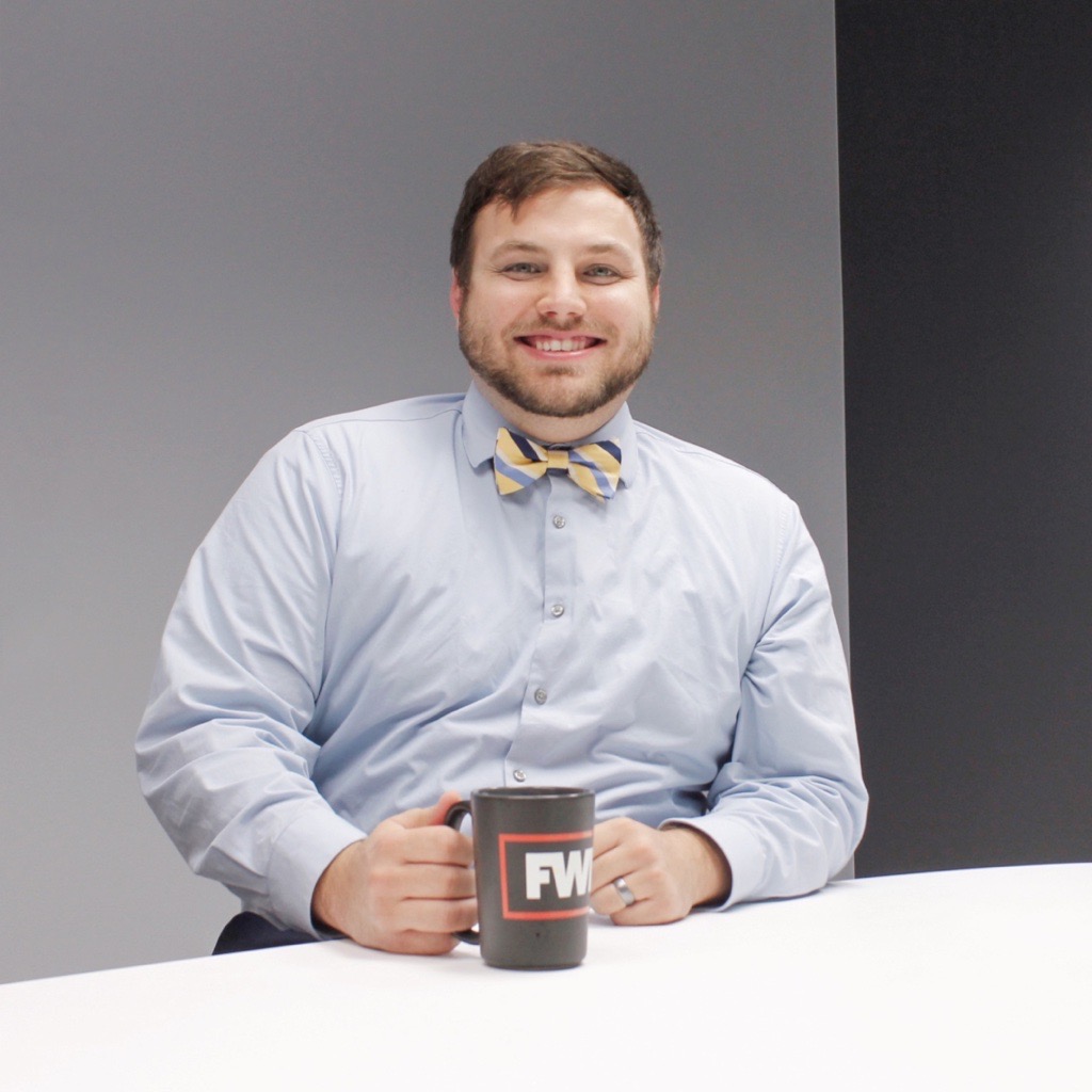 Jacob Hollemans wearing a bowtie, smiling and holding an FWF mug.